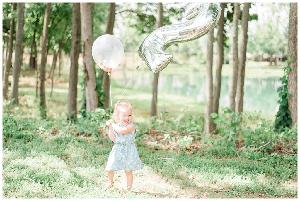 baby girl holding balloons
