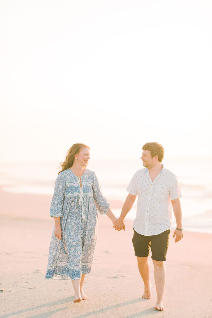 husband and wife walking together at sunrise on the beach