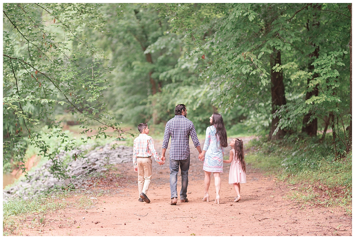 family walking away through woods holding hands