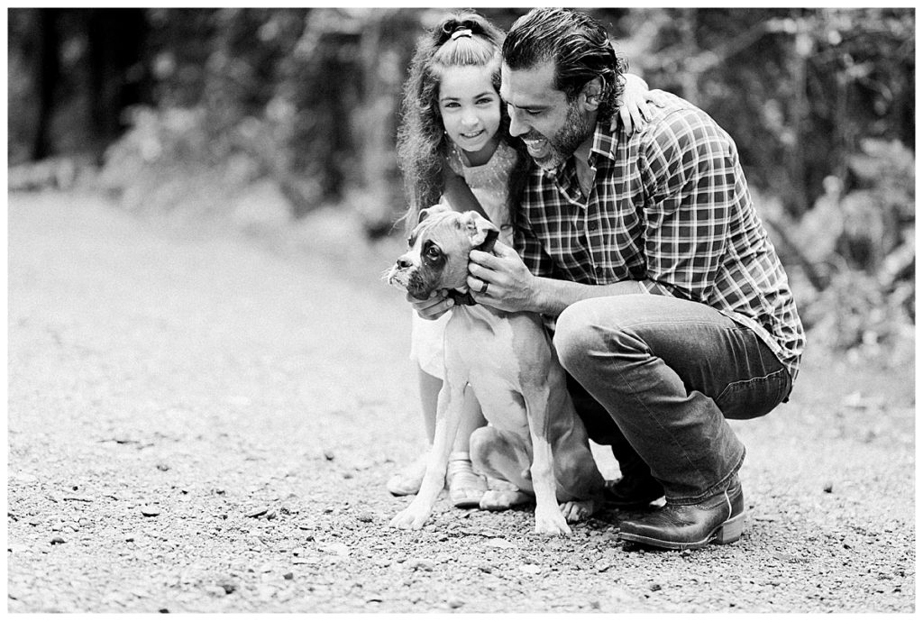 father and daughter playing with boxer puppy black and white
