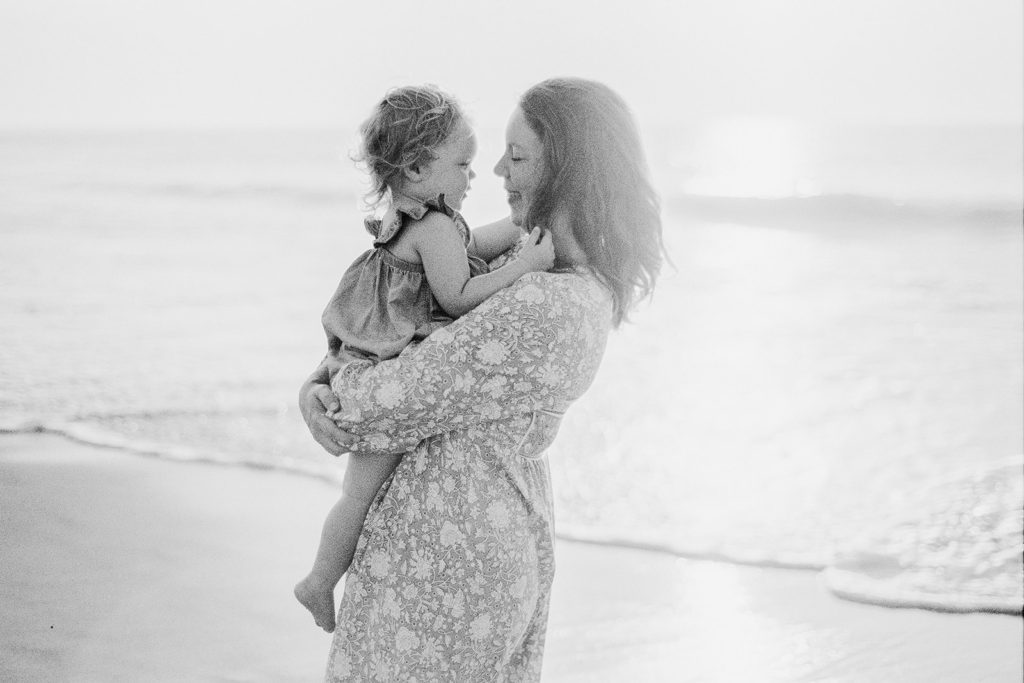 mother holding daughter at sunrise on the beach