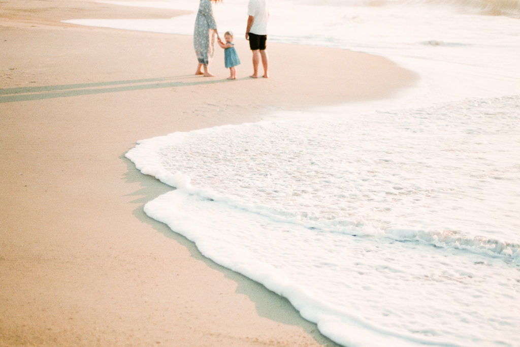 family walking on the beach at sunrise