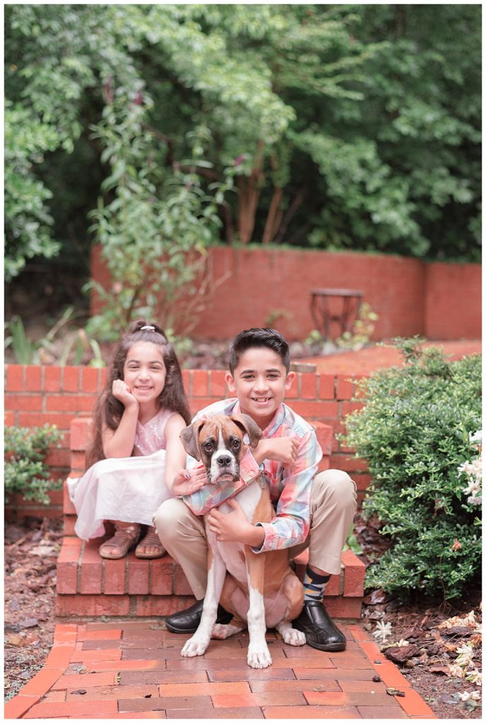 kids sitting on brick steps with boxer puppy