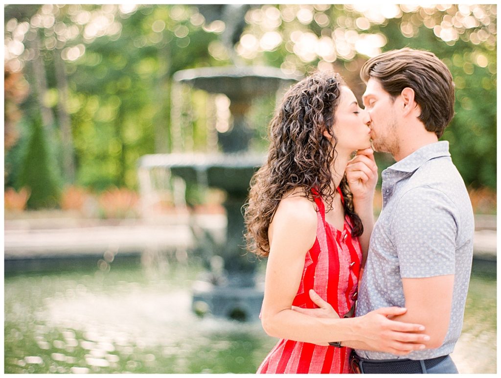 engaged couple kissing in front of duke gardens fountain