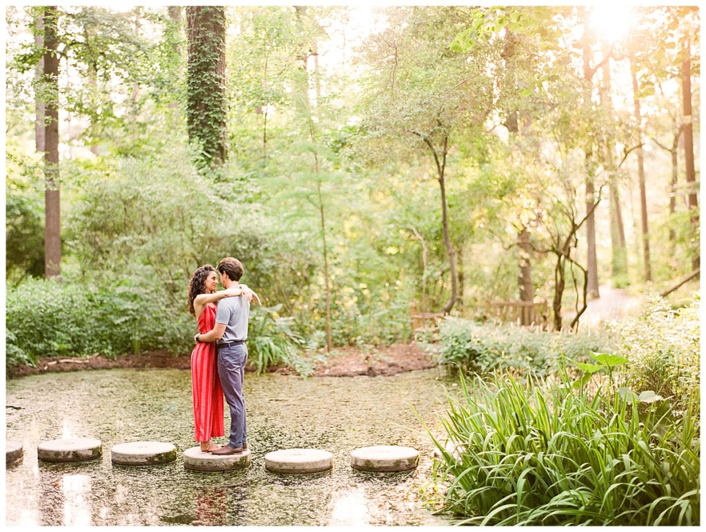 engaged couple hugging on stepping stones over pond