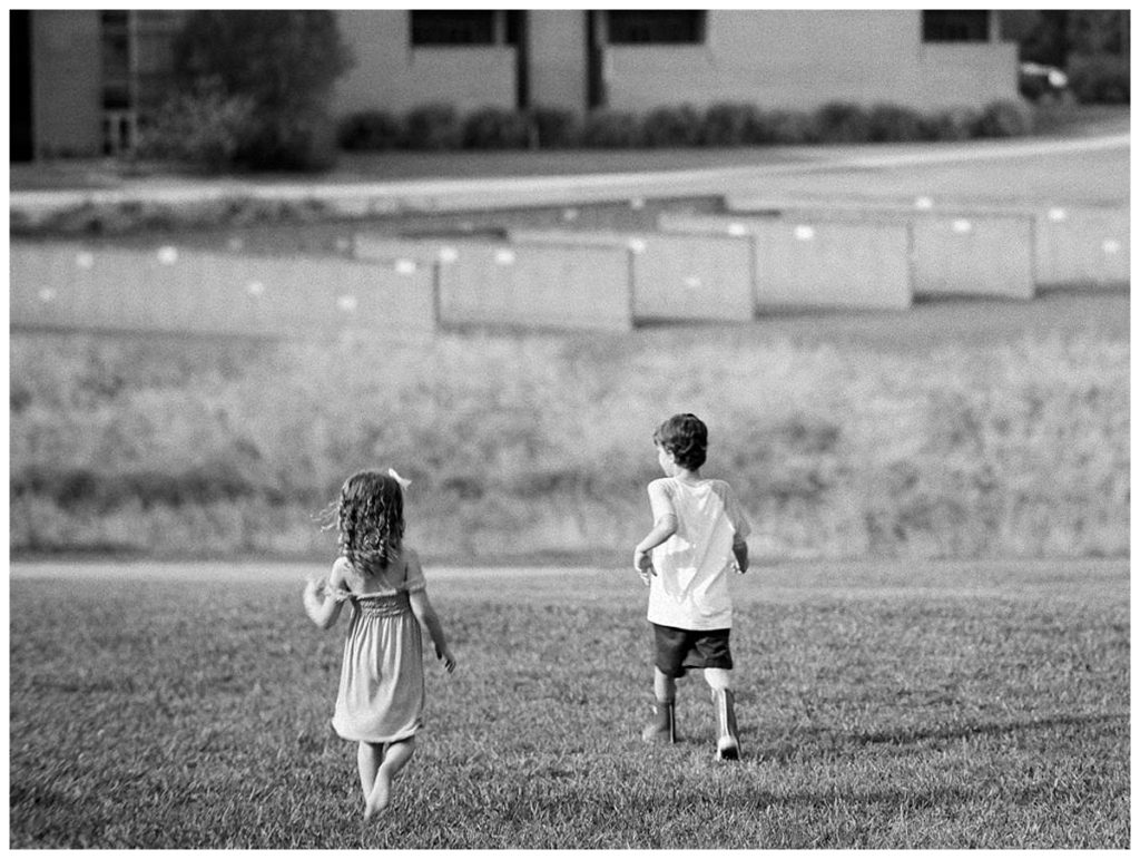 children exploring in tall grass black and white photography