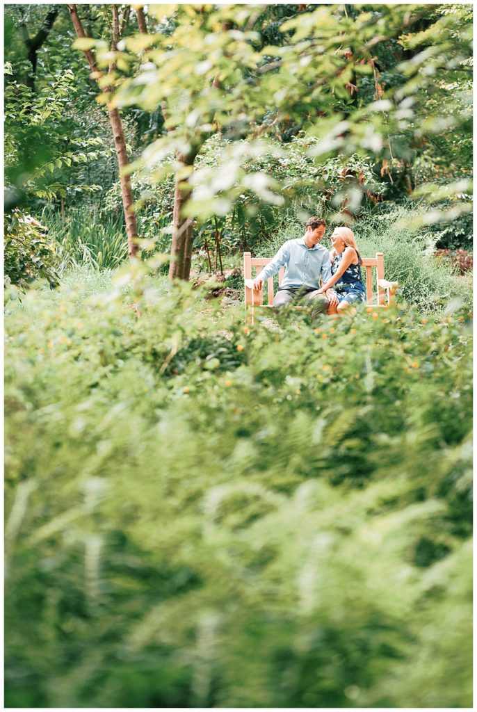 engaged couple sitting on bench at unc arboretum