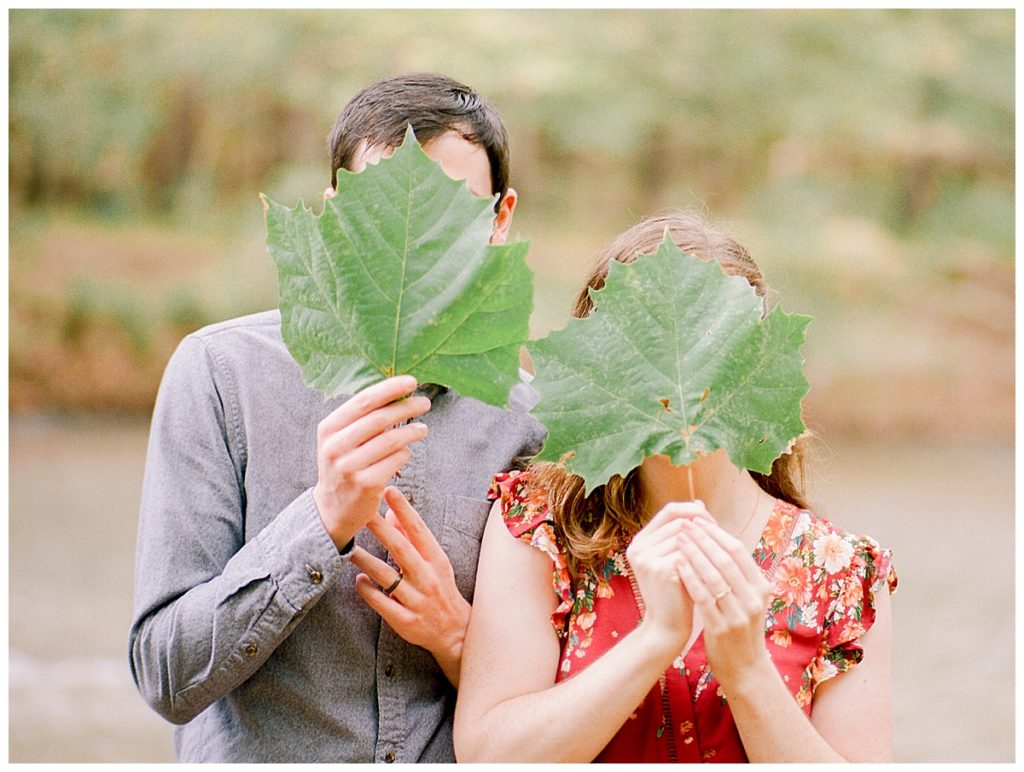 couple holding leaves in front of face