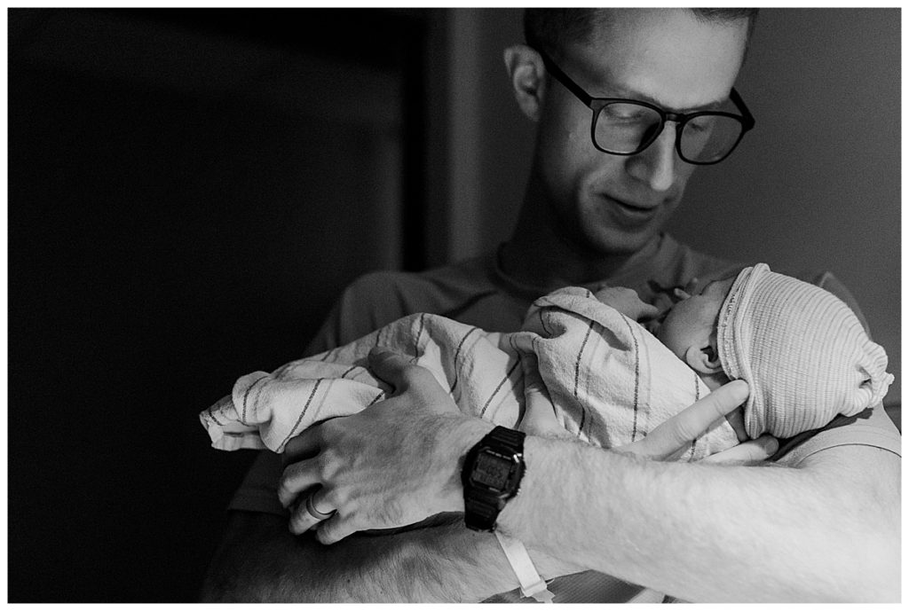 dad holding newborn son black and white photography