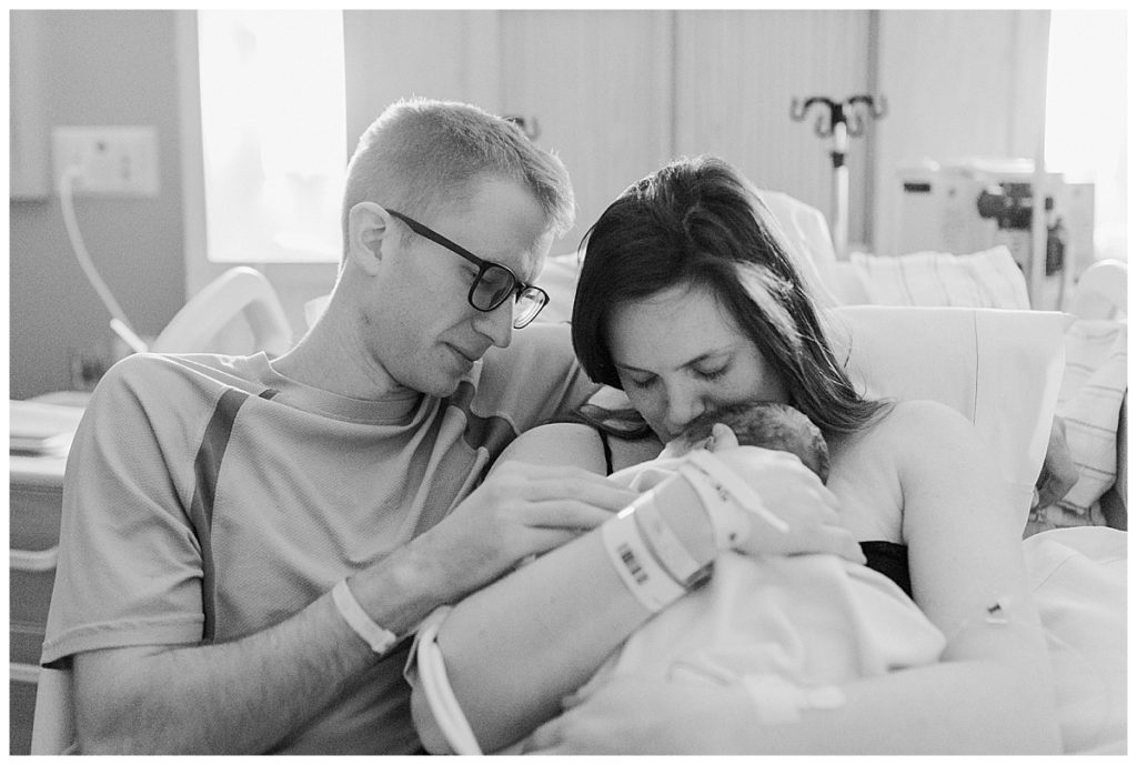 mom and dad with baby in hospital bed
