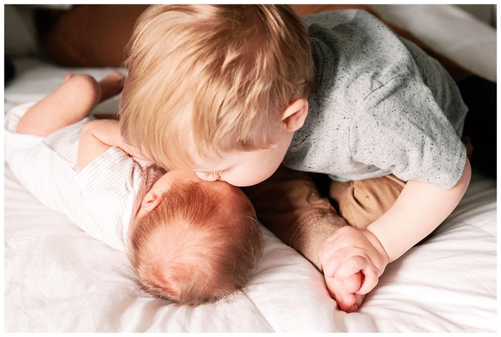 big brother kissing baby on head