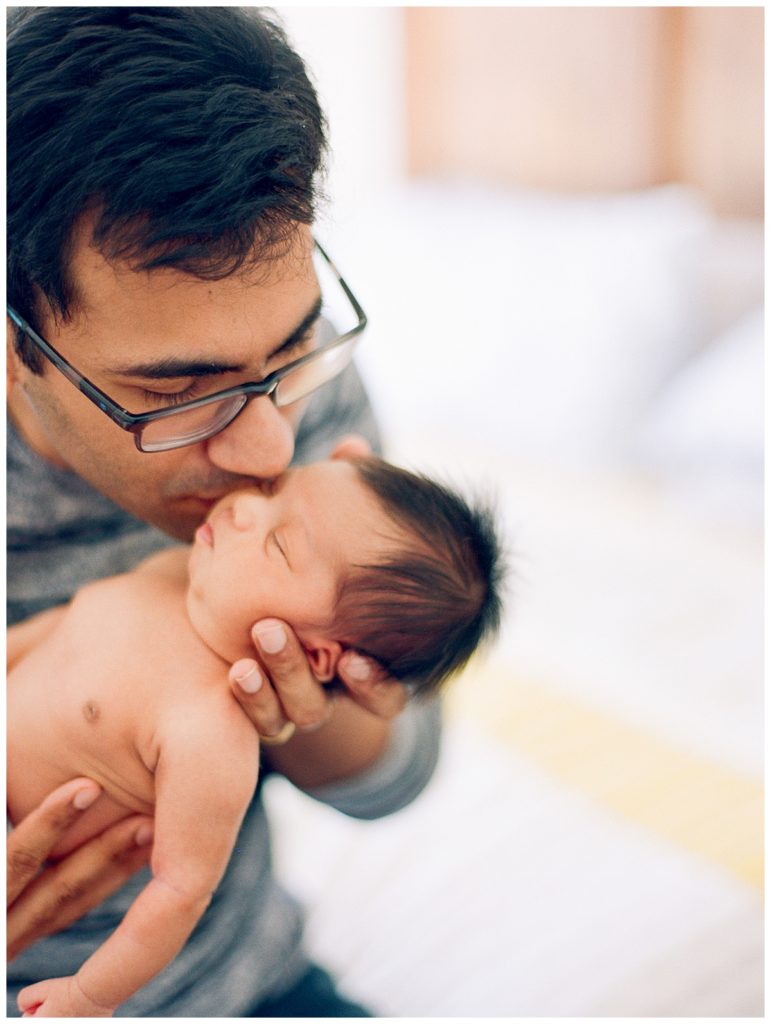 father kissing newborn baby girl