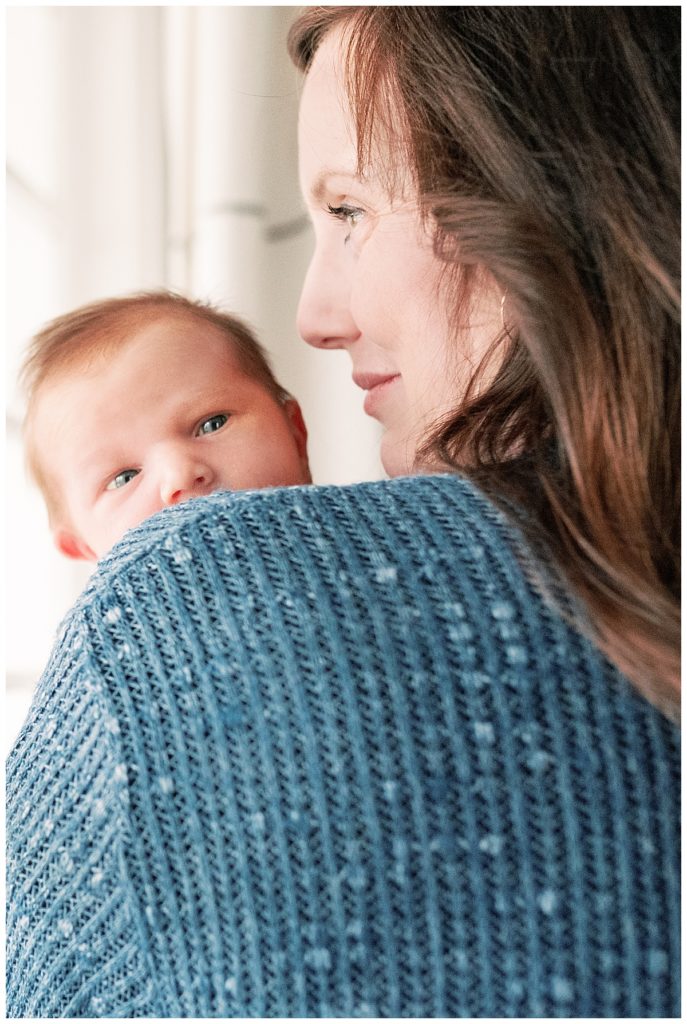 newborn peeking over mom's shoulder