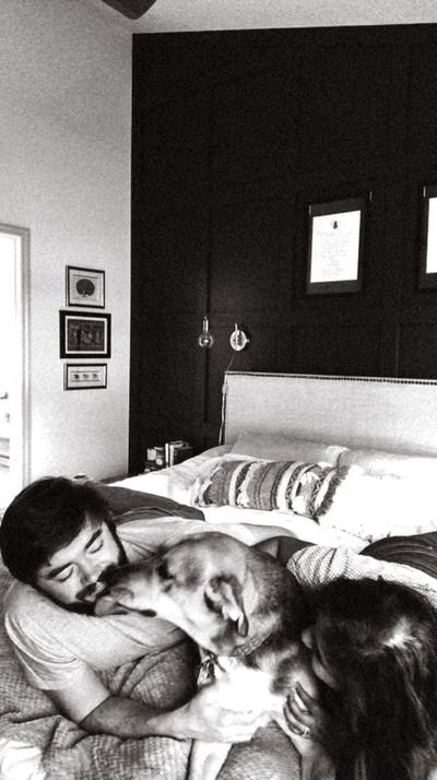couple on bed with dog licking