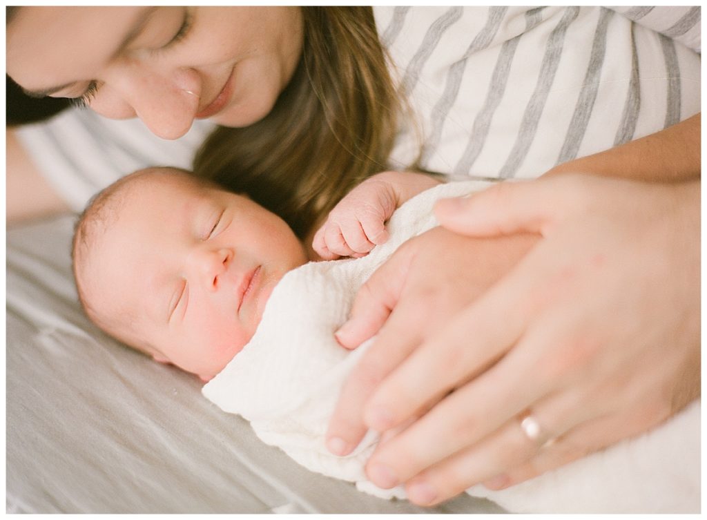 Mom laying with newborn baby on bed
