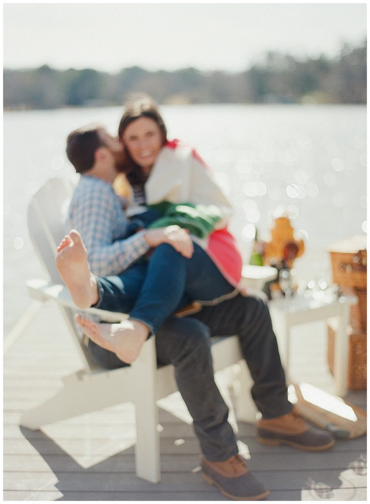 engaged couple cuddling on dock