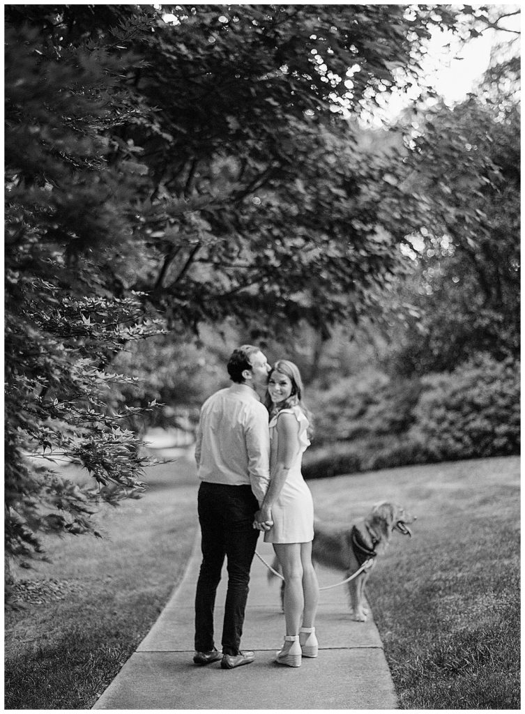 engaged couple walking dog at sunset